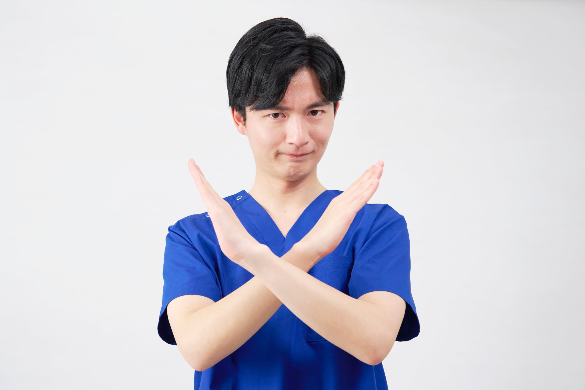 インプラント治療が受けられないことを知らせる手でバツをした歯科医