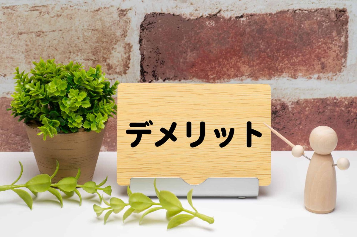 木の板に書かれたデメリットの文字を棒で示す木の人形