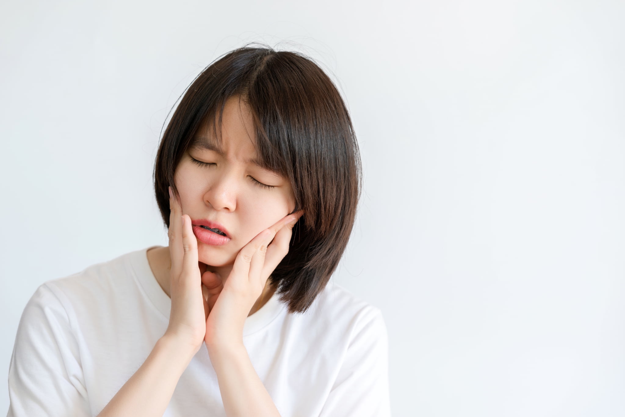 矯正中の歯を痛がる女性